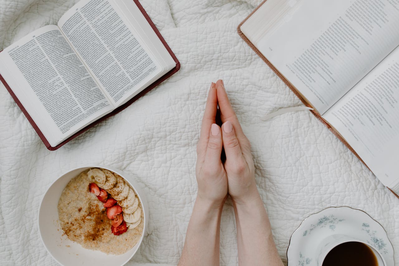 creative-01 A serene morning scene with a person praying, an open Bible, oatmeal, and coffee.